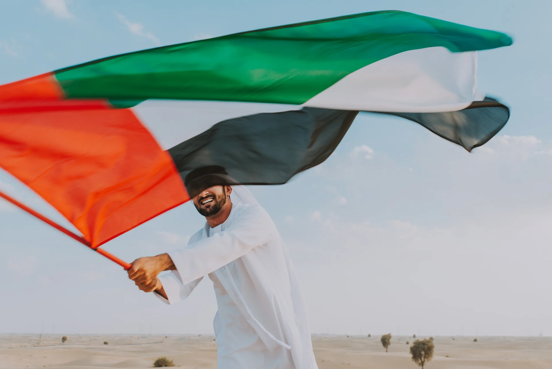 An Emirati man waving the UAE flag in the desert